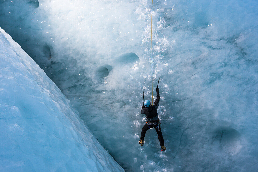 Man climbing a steep glacier ice at the glacier Gigjokull. South Iceland.