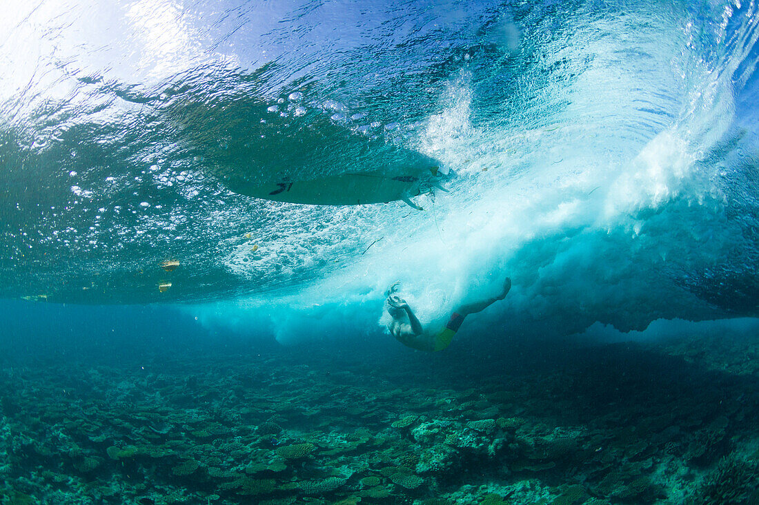 Surfers wiping out on the shallow reef in maldives