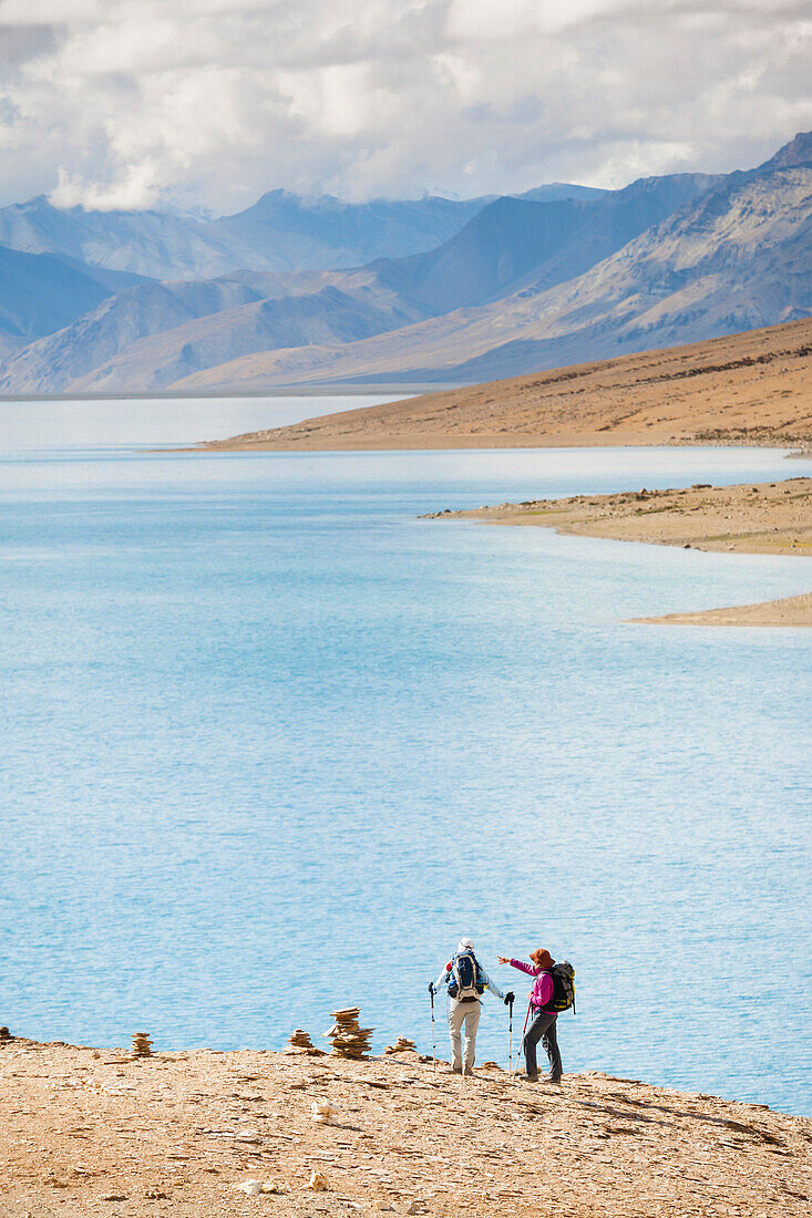 Two hikers are looking at the Tsomoriri Wetland Conservation Reserve (Lake Moriri), in the Changthang (literal meaning, northern plains) region of Ladakh, India.
