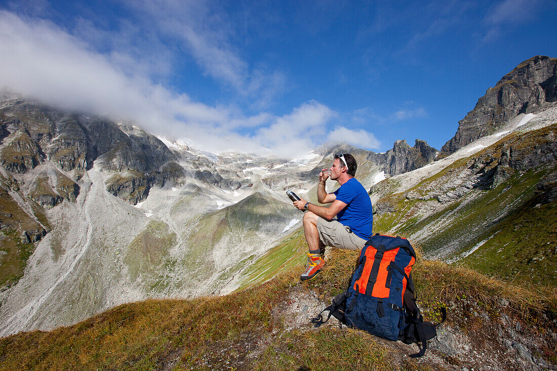 A male hiker drinks a tea during the Glocknerrunde, a 7 stage trekking from Kaprun to Kals around the Grossglockner, the highest mountain of Austria.     Located in the heart of the Hohe Tauern National Park which contrasts impressive, glacier-covered hig