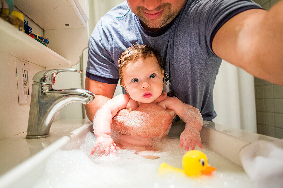 Close up of Caucasian father bathing baby girl in sink