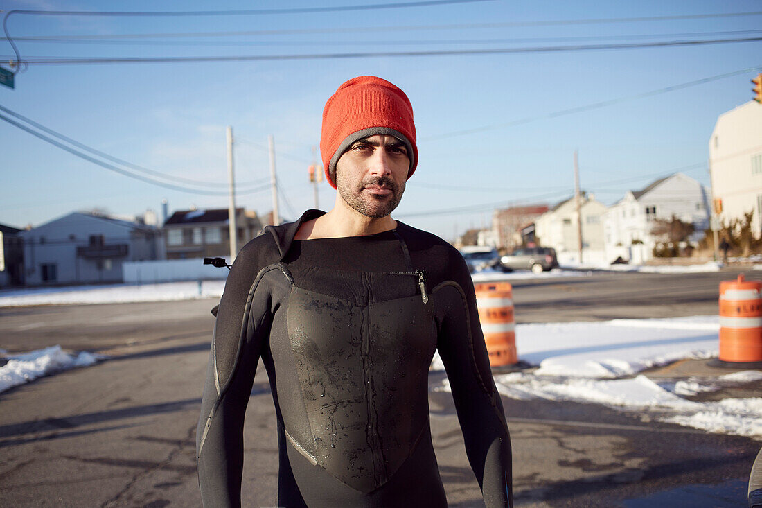 Black man in wetsuit standing in snow