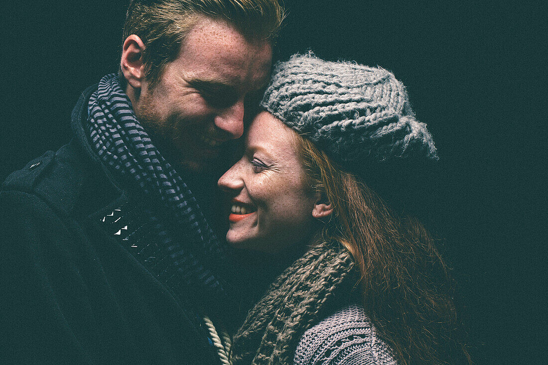 Smiling couple wearing warm clothing hugging