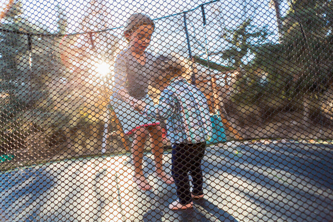 Caucasian brother and sister jumping on trampoline