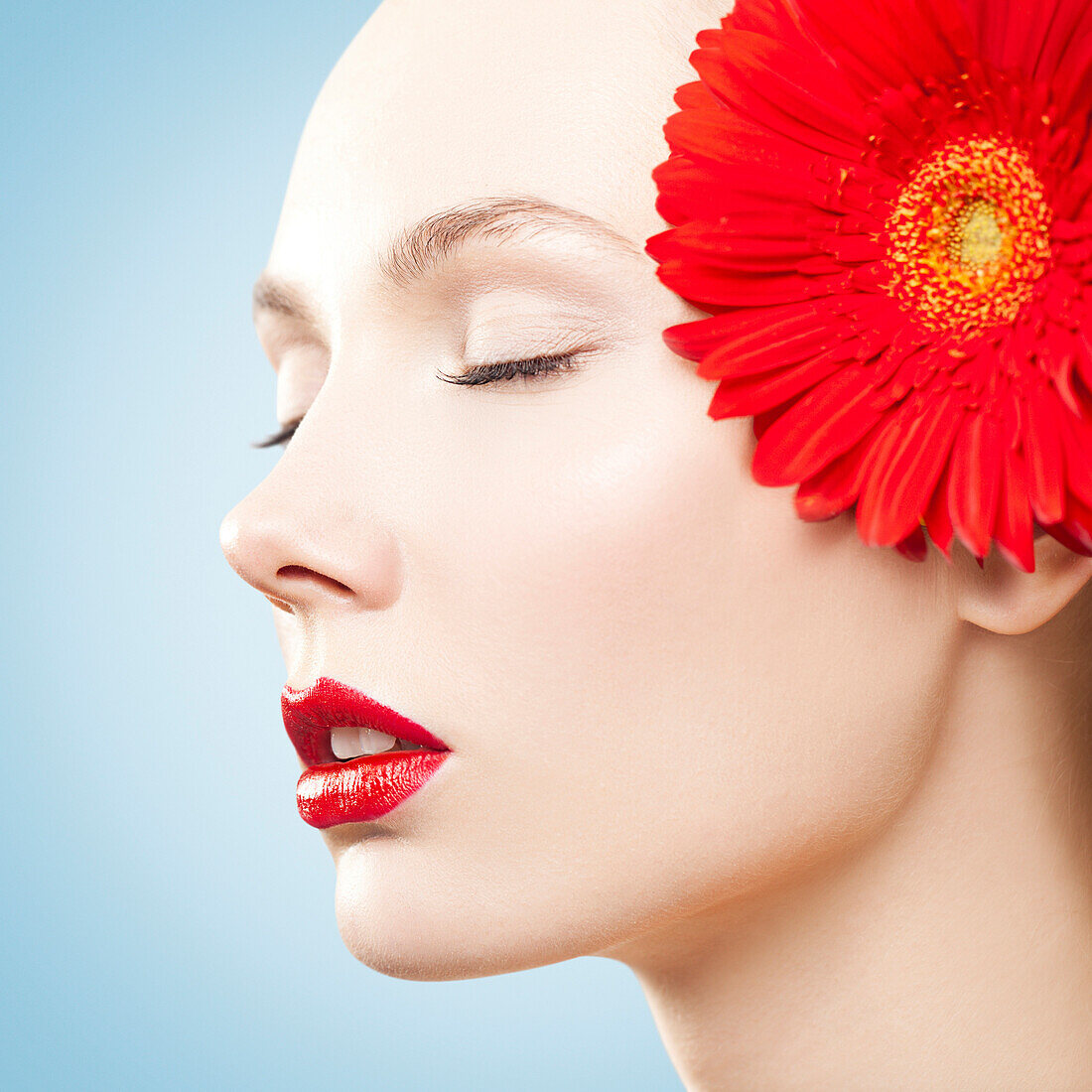 Kaukasische Frau mit rotem Lippenstift und passender Blume