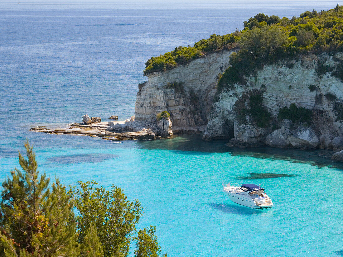 View from hillside over secluded Voutoumi Bay, solitary boat at anchor, Antipaxos, Paxi, Corfu, Ionian Islands, Greek Islands, Greece, Europe