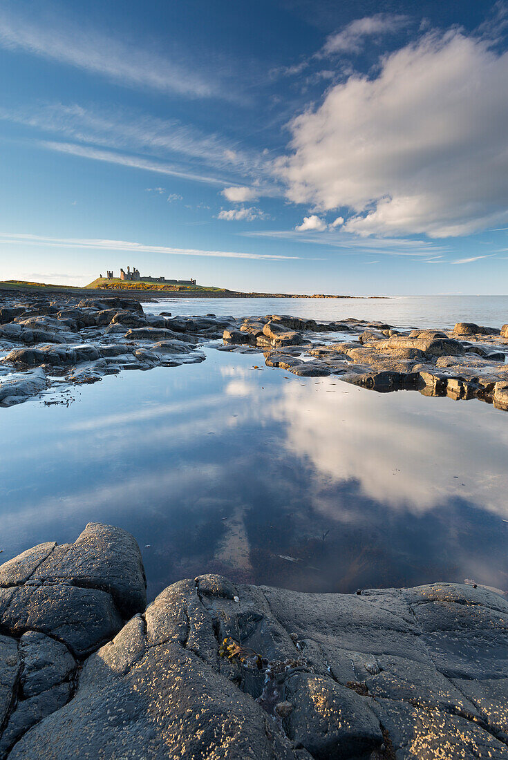 Rocky coastline with rockpools near Dunstanburgh Castle, Craster, Northumberland, England, United Kingdom, Europe