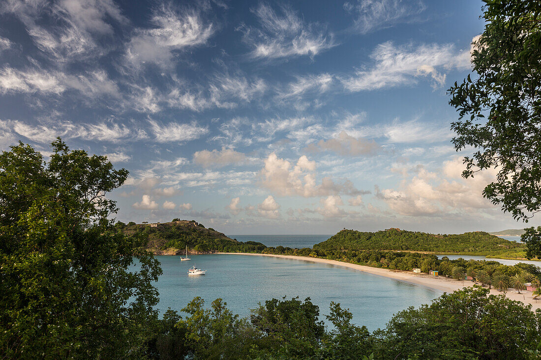 The clouds are illuminated by the setting sun on Deep Bay a stretch of sand hidden by lush vegetation, Antigua, Leeward Islands, West Indies, Caribbean, Central America