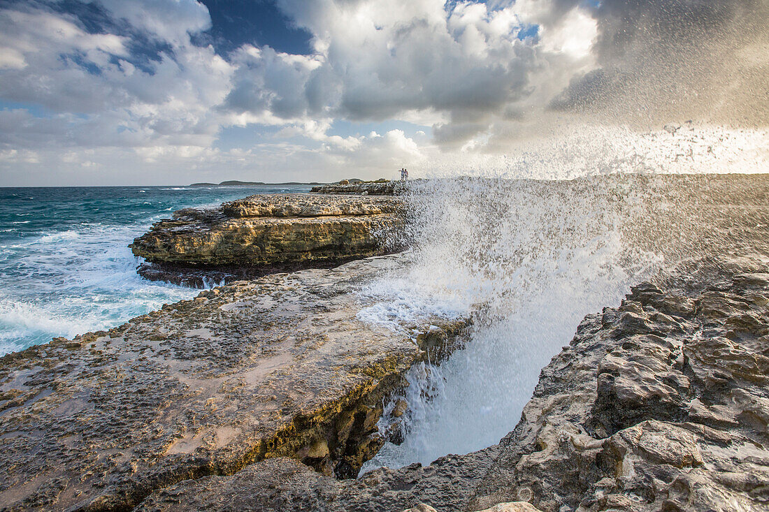 A wave created by the strong wind squirts water over Devils Bridge, a coral bridge created by wind and the power of sea, Antigua, Leeward Islands, West Indies, Caribbean, Central America