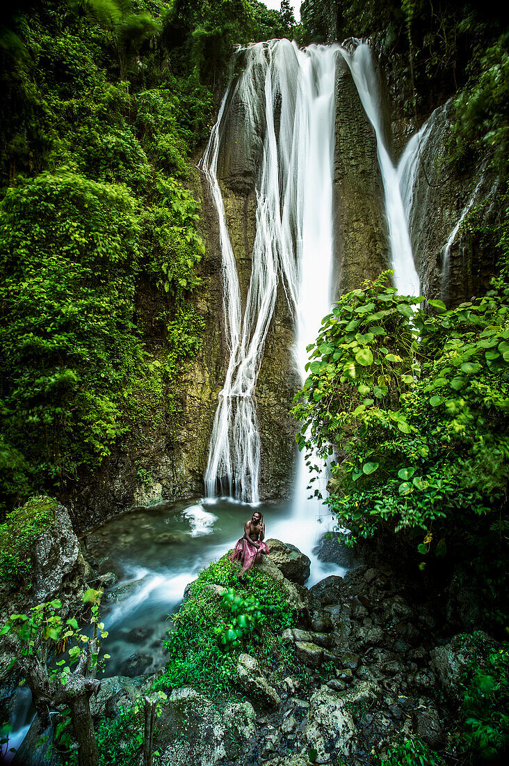 A waterfall on Tanna Island with a man in traditional costume in the foreground, Tanna Island, Vanuatu