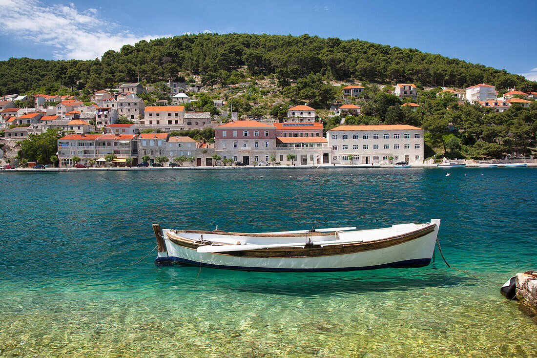 A small boat rests in the tranquil clear water, Pucisca, Island of Brac, Croatia