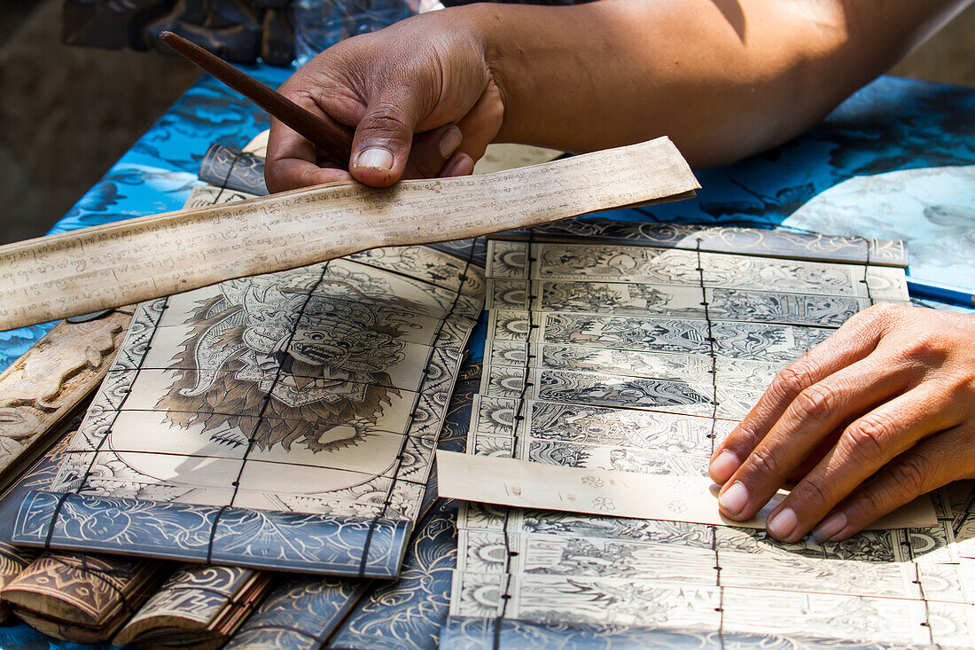 Man carving the ancient tales and the famous Ramayana story in Sanskrit on lontar leaves, Tenganan Pegringsingan, Bali, Indonesia