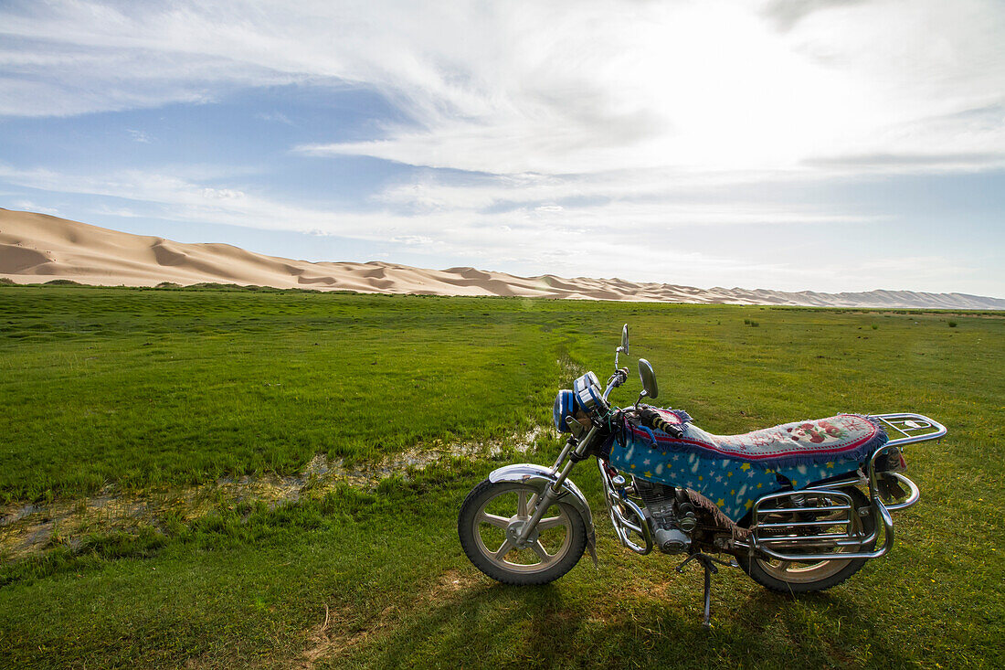 Motorcycle parked in Seruun Bulag oasis by the sand dunes of Khongoryn Els, Gobi Gurvansaikhan National Park, Ömnögovi Province, Mongolia