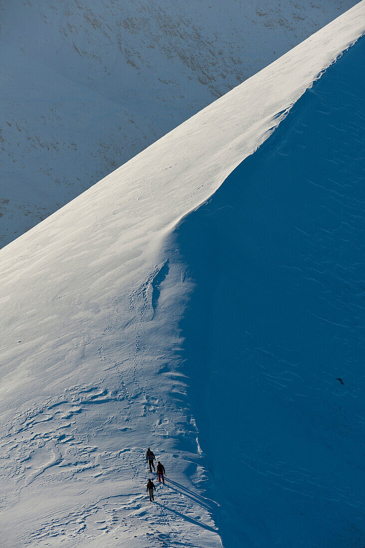 Walkers climbing snowy ridge of Sgorr Dhearg in winter near Glen Coe, Highlands, Scotland