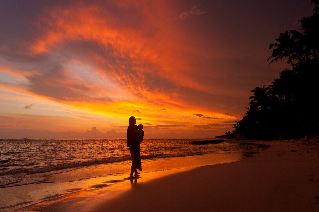 Mother and baby watching sunset on beach, near Unawatuna, Thalpe, Sri Lanka