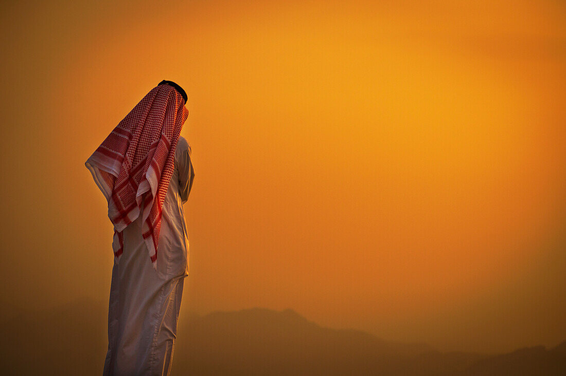 Saudi standing to watch the glowing orange sunset, Taif, Saudi Arabia