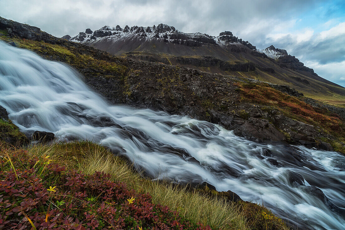 'A large stream runs down a hillside creating a waterfall along the Strandir Coast in the West Fjords of Iceland; Iceland'