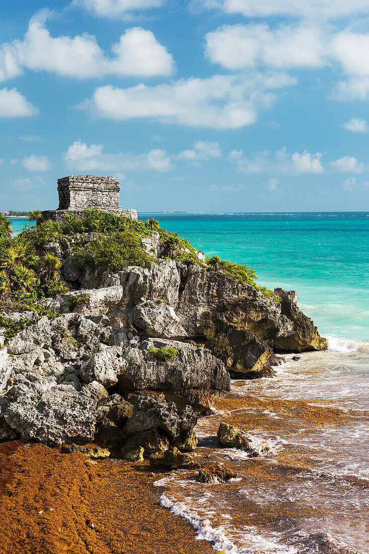 'Ancient Mayan Temple on rock cliff overlooking the ocean with blue sky and clouds; Tulum, Quintana Roo, Mexico'