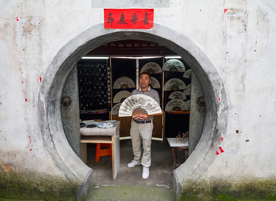 Artist holding a fan with a traditional Chinese brush painting, Xidi, Anhui, China