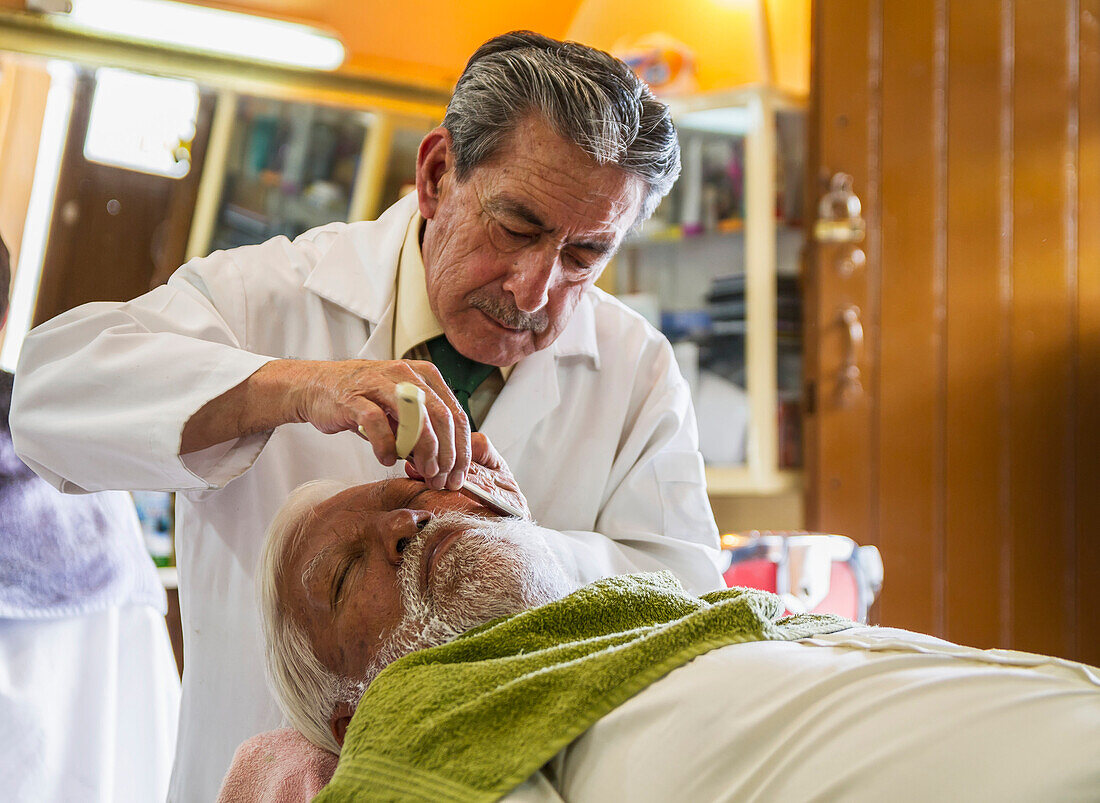 Man getting a shave by Nelson Eduardo Pinto, barber in the Peluquería Amazonas barber shop under the Palacio de Carondelet Presidential Palace), Quito, Pichincha, Ecuador