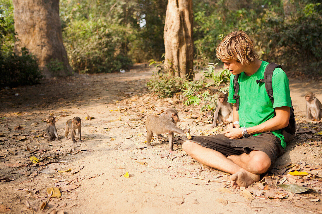 'A tourist plays with the wild monkeys that live in the Monkey Forest, located in the Xe Champhone region; Laos'