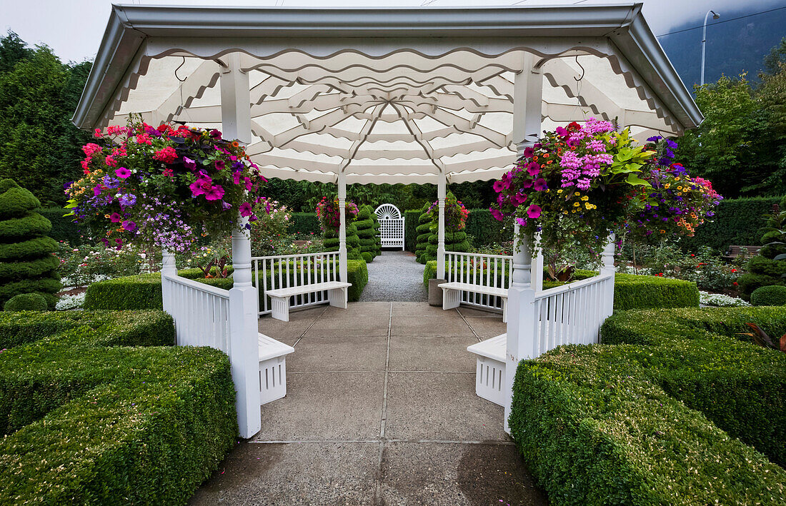 'White gazebo with hanging flower baskets in Minter Gardens; Rosedale, British Columbia, Canada'