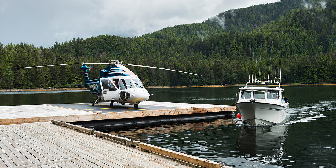 'Helicopter on a dock alongside a fishing boat; Queen Charlotte Islands, British Columbia, Canada'