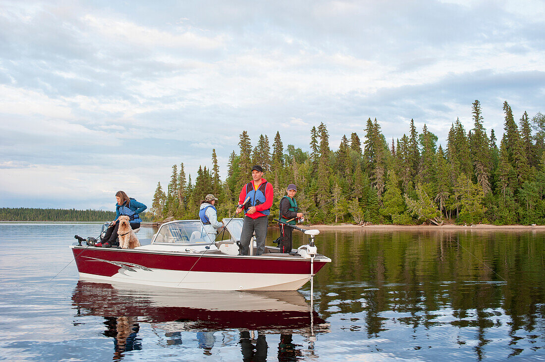 'A family fishing from their motorboat on a calm lake in Northern Ontario; Ontario, Canada'