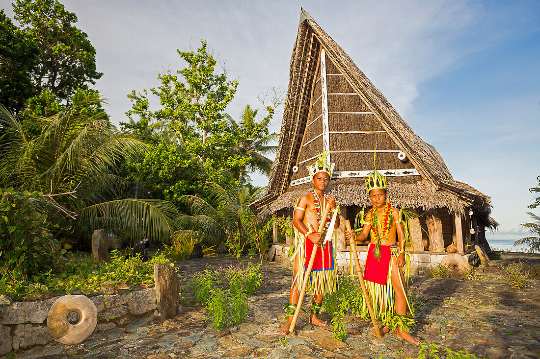 'These two young boys in traditional outfits for cultural ceremonies are standing in front of a Men's House; Yap, Micronesia'