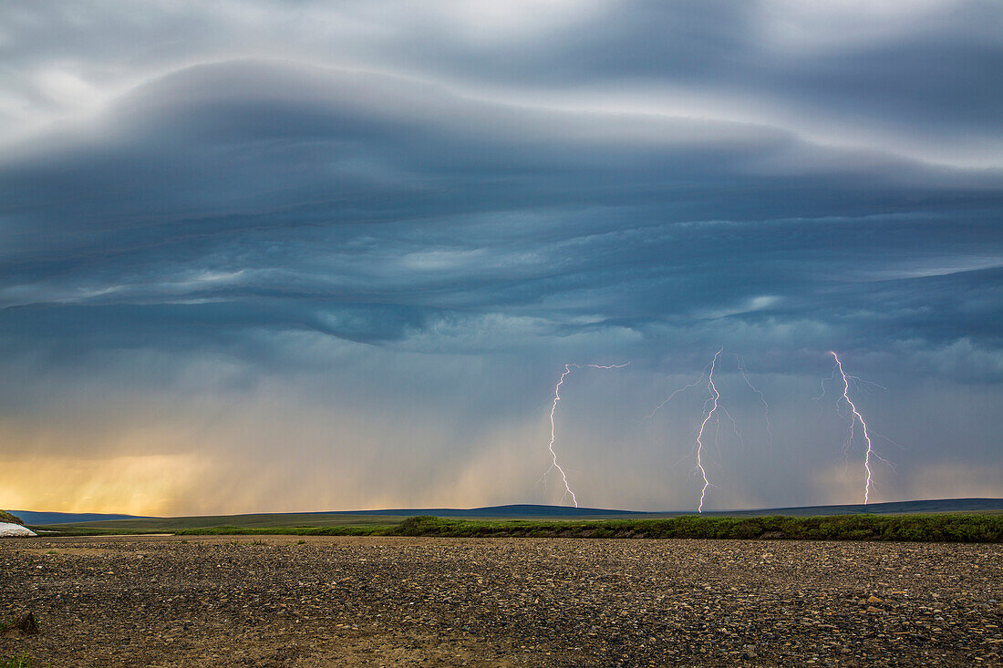 Lightning bolts descend from dark clouds over the tundra of Alaska's northwest arctic and the Kokolik River, Kokolik National Petroleum Reserve, Arctic Alaska, USA.