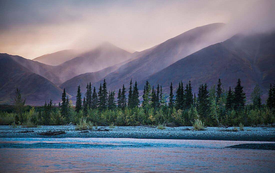 Rain and snow squalls race over the mountains during sunset on the Kelly River, in the western Brooks Range of Noatak National Preserve, Alaska, USA.