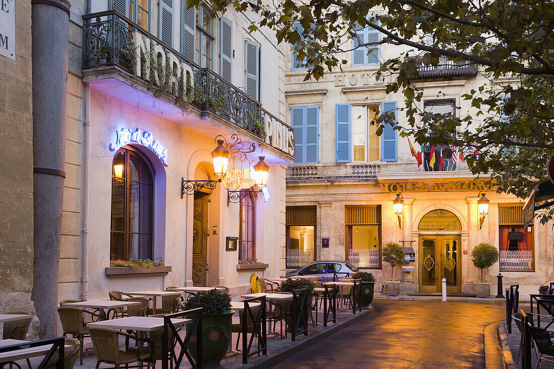 Outdoor patio seating on an illuminated street at dusk, Arles, Provence-Alpes-Cote D'Azur, Bouches-Du-Rhone, France