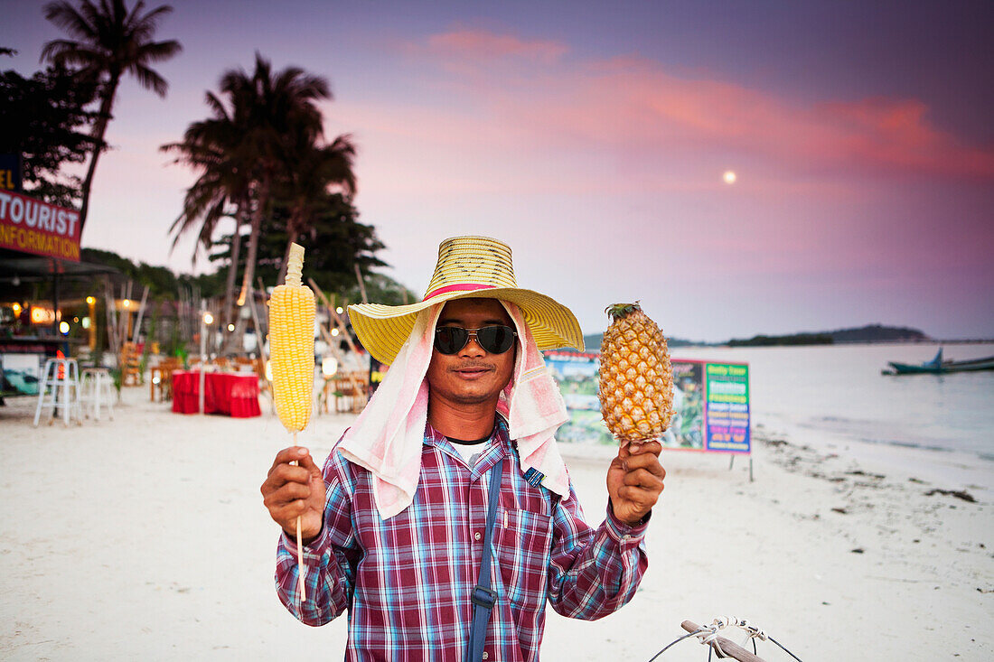 A local vendor selling pineapple and corn on the beach of Chaweng at sunset, Chaweng, Ko Samui, Thailand