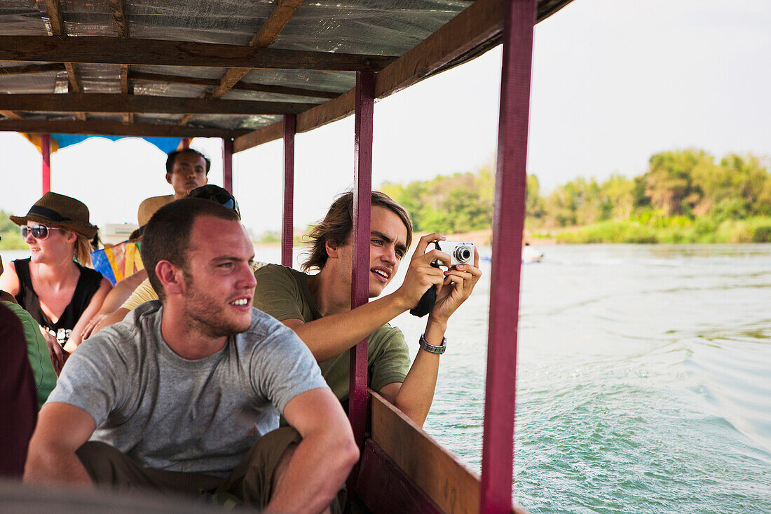 Tourists take a ferry on the Mekong River to the Island of Don Det, Laos