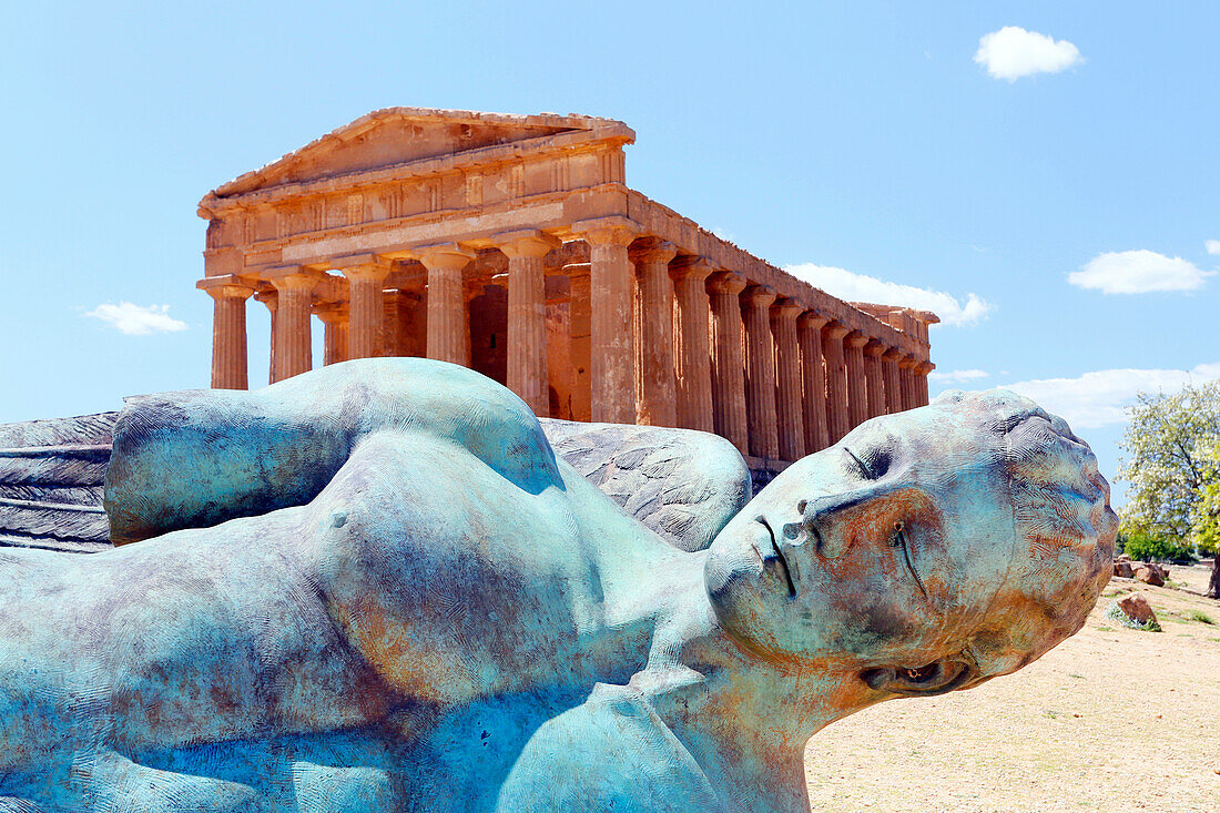 Italy, Sicily, Valley of the Temples, Sculpture by Igor Mitoraj representative Icarus fell, In the background the Temple of Concordia