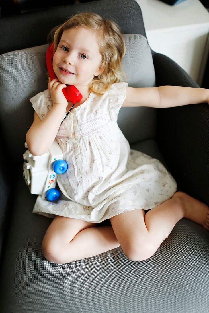 A 3 years old girl posing with a toy phone