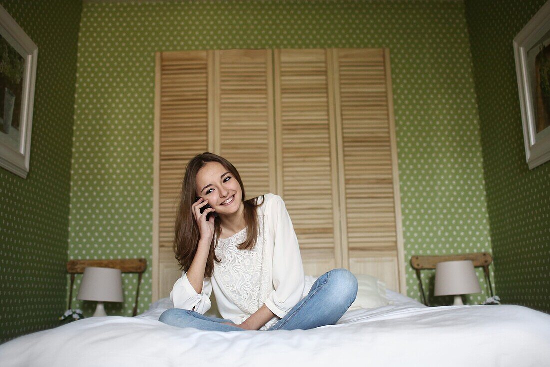 A teenage girl phoning on her bed