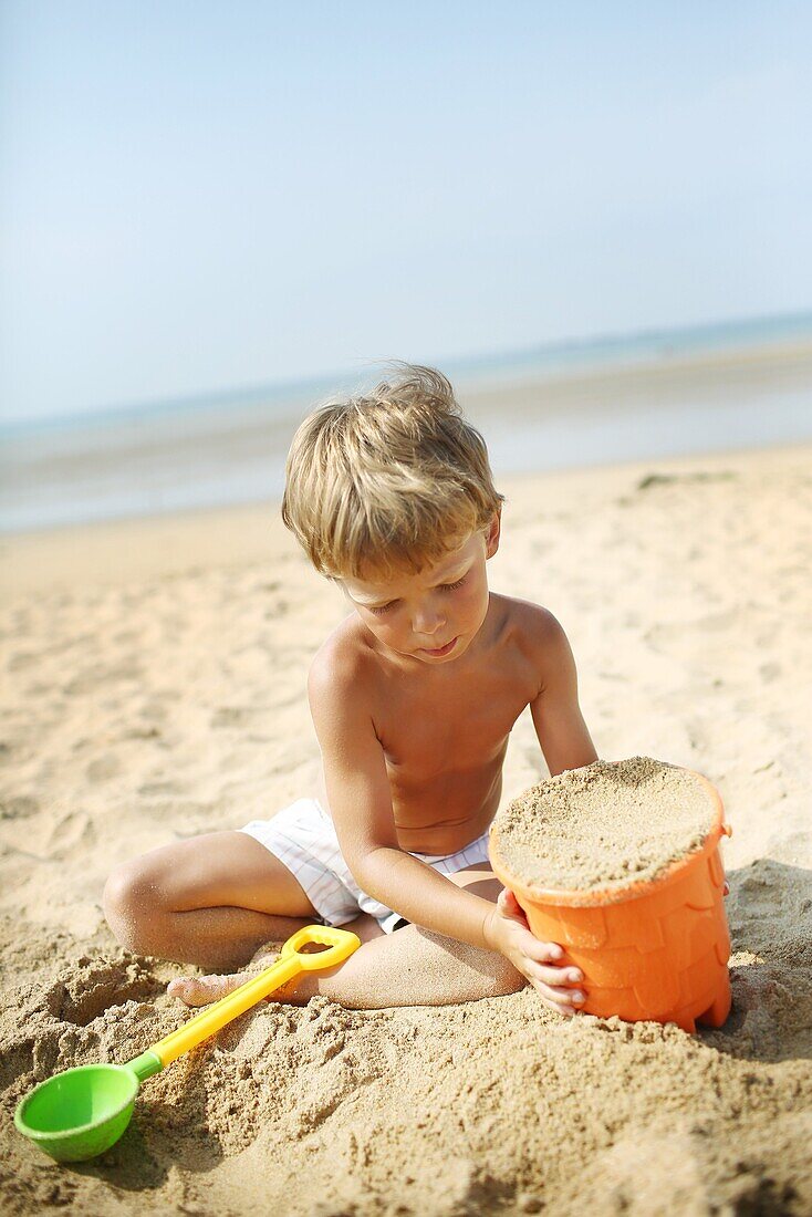 Little boy at the beach playing in the sand