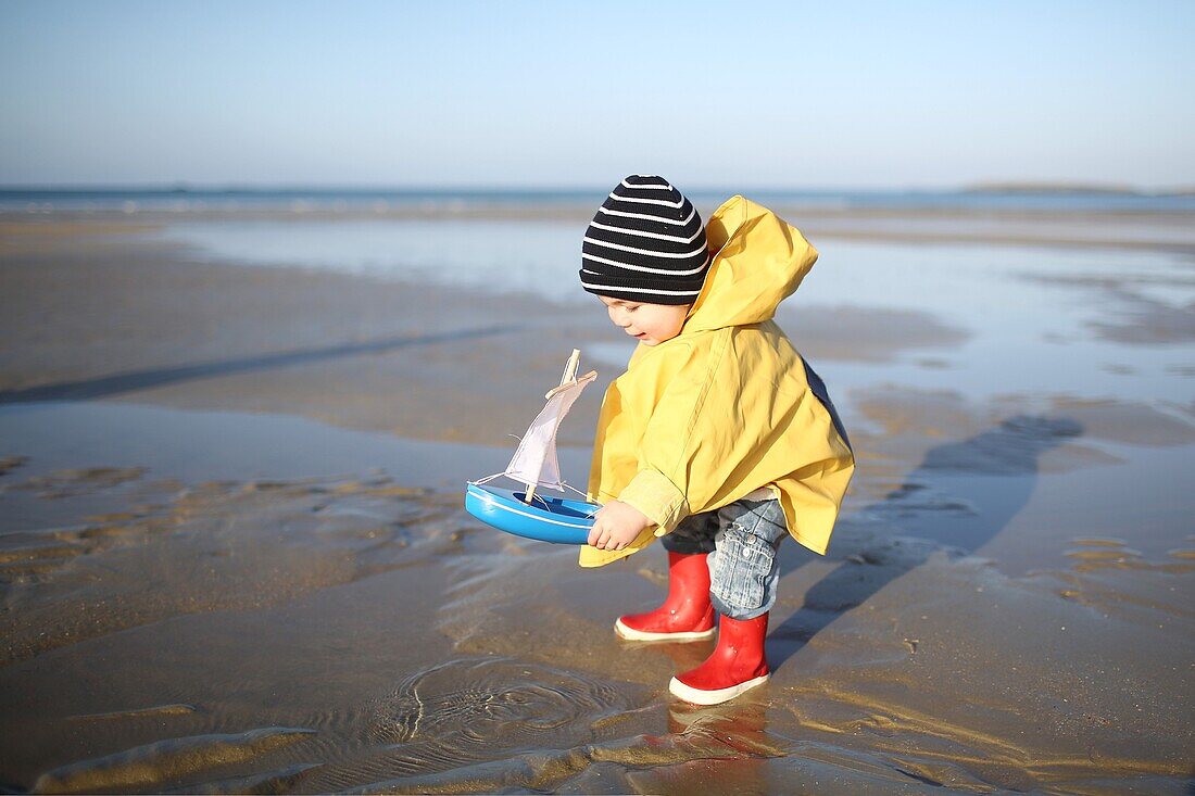 A 1 year old boy plays on the beach