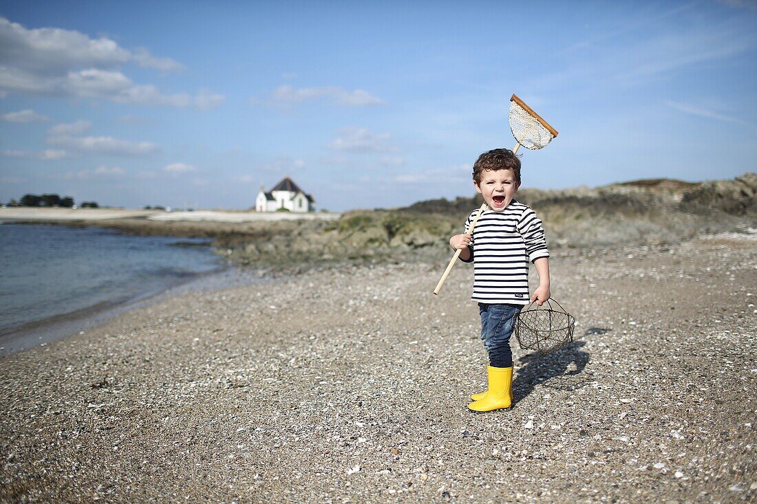 3 years old boy fishing with a net at the beach
