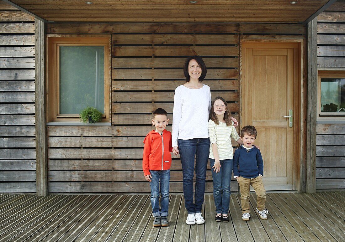 A mother and her three children at the front door of their house