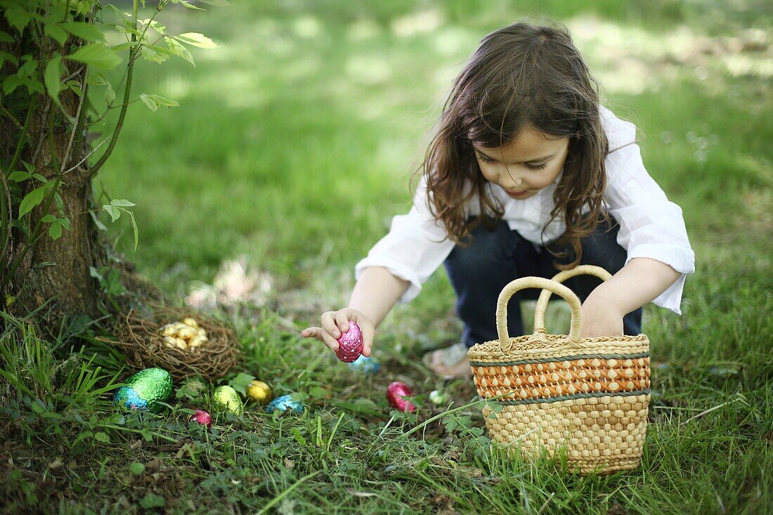 A 5 years old girl picking up Easter eggs in the countryside