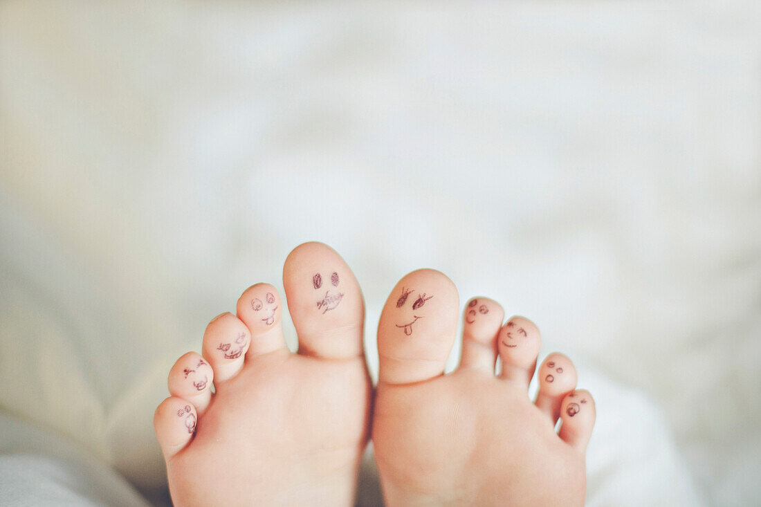 Toes of Caucasian girl with smiley face drawings