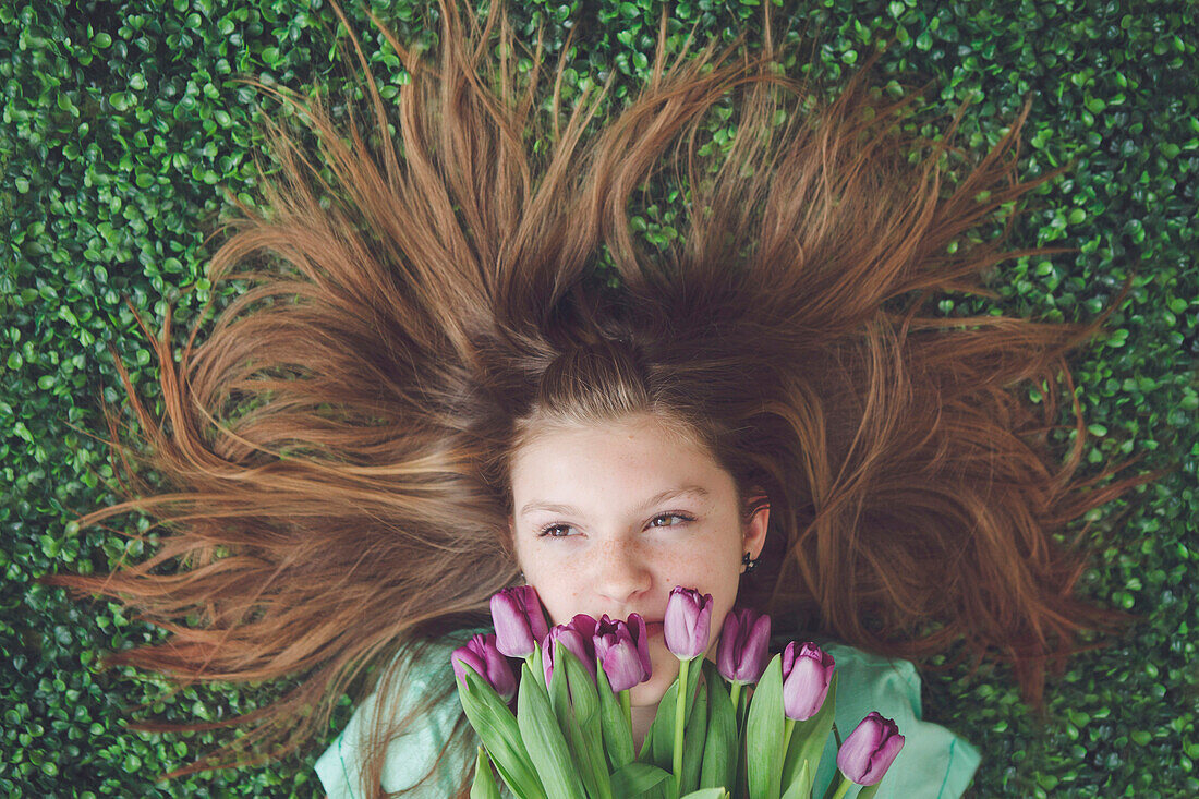 Caucasian girl with tulips laying in grass
