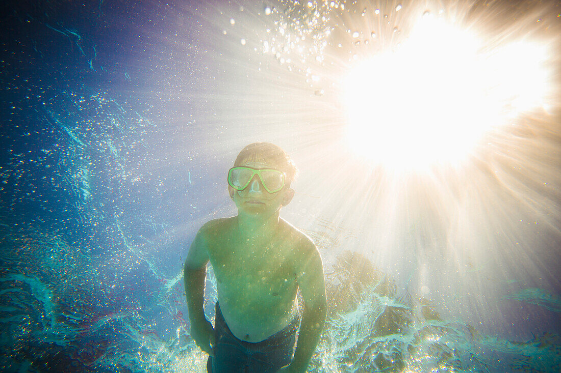 Caucasian boy swimming underwater in swimming pool