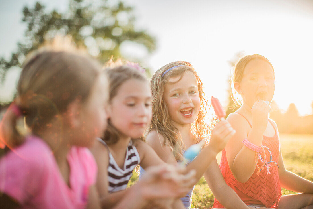 Girls eating flavored ice in sunny field