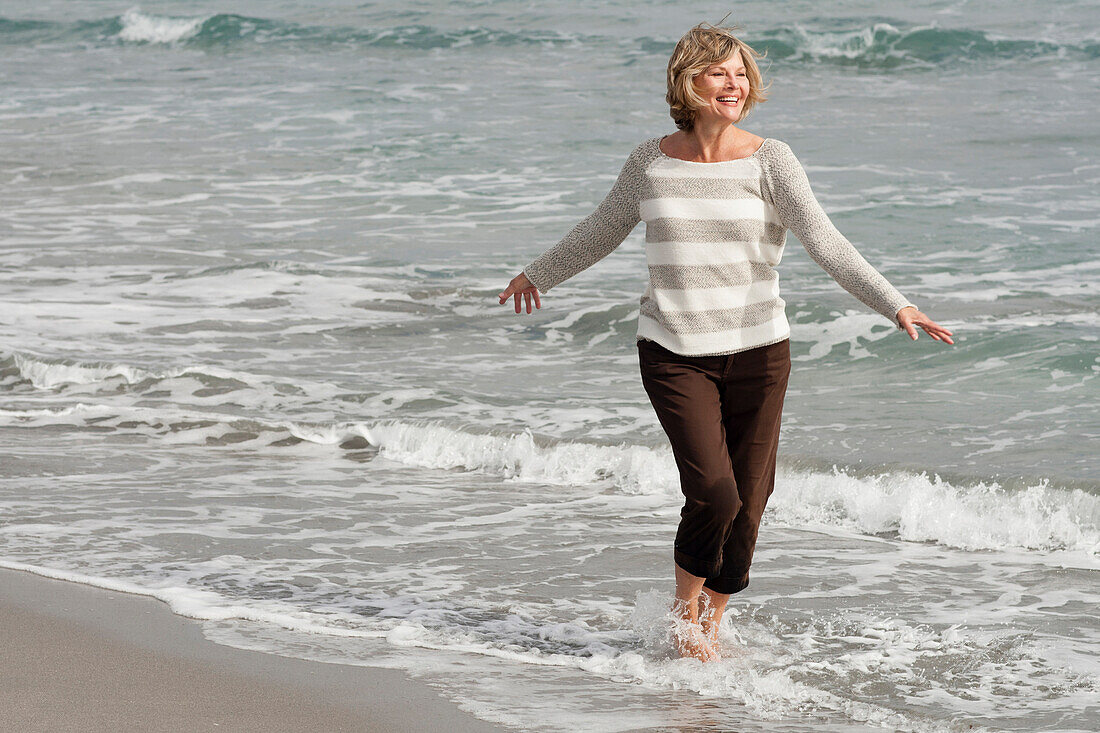 Caucasian woman wading on beach