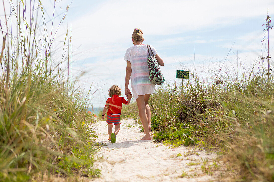 Caucasian mother and baby son walking on beach