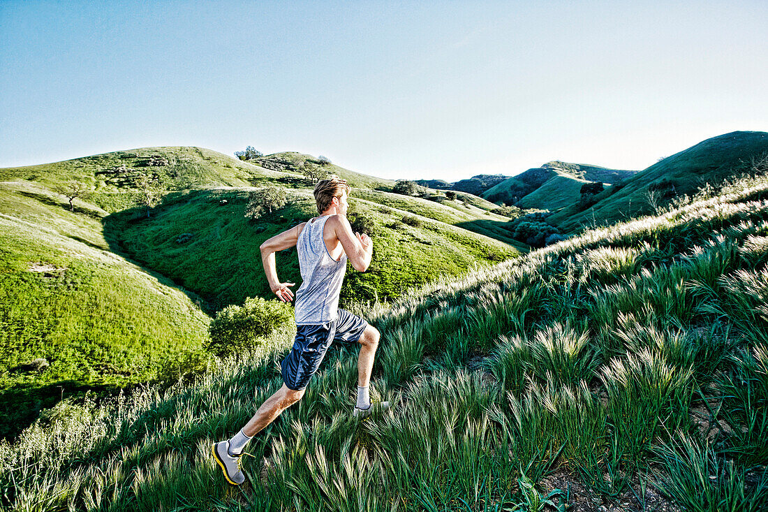 Caucasian athlete running on rural hills