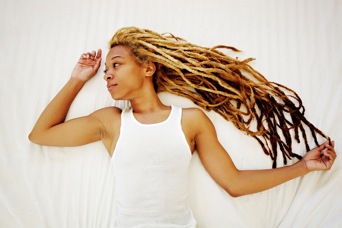 Black woman with dreadlocks laying on bed